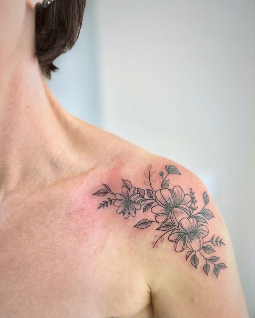 Fine line floral tattoo across the shoulder